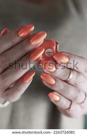 Female beautiful hand with long nails and a neon orange nail polish