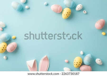 Easter party concept. Top view photo of easter bunny ears white pink blue and yellow eggs on isolated pastel blue background with copyspace in the middle Royalty-Free Stock Photo #2263730187
