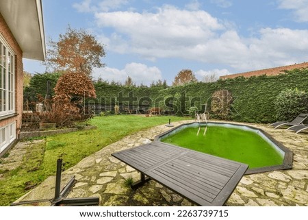 a backyard with a pool in the middle and green grass on the ground next to the pool is surrounded by trees