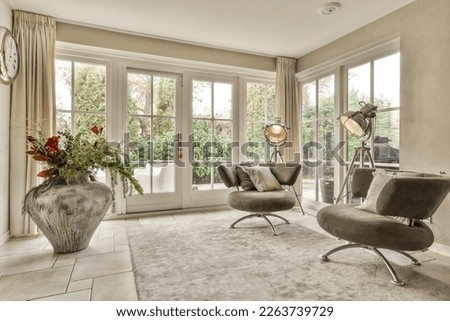 a living room with two chairs and a large flower vase on the floor in front of the window looking out to trees Royalty-Free Stock Photo #2263739729