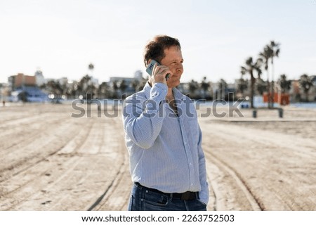 Businessman Talking On Phone, using smartphone mobile apps texting message, surfing social media tech standing in urban city on modern street outdoors.