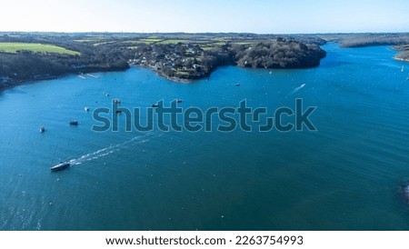 Aerial view of the Helford river with boats anchored and moving. Fields and trees visible to the horizon