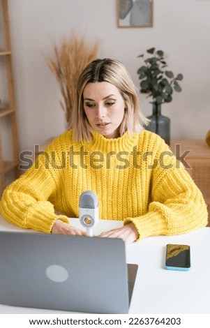 Young woman with laptop recording podcast