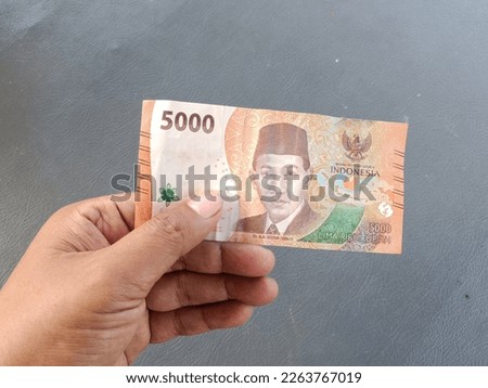 hand holding a banknote worth 5,000 Rupiah, the latest edition of 2022