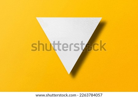 White paper cut into triangle shape, play button set on yellow paper background. Royalty-Free Stock Photo #2263784057