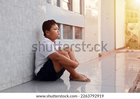 Depressed boy sitting on the terrace floor Royalty-Free Stock Photo #2263792919
