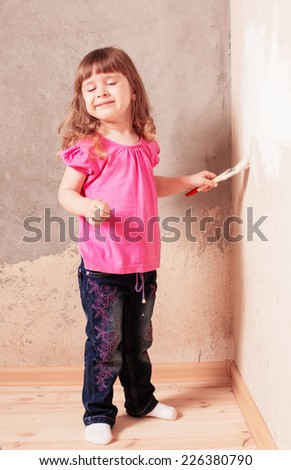 little child with paintbrush on background old wall