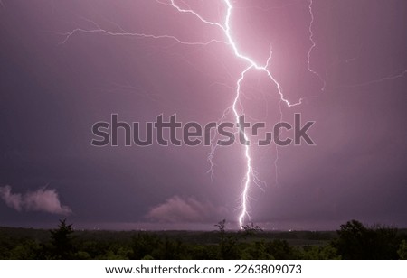 This awe-inspiring stock photo captures the incredible power and beauty of a large lightning bolt striking the ground in the Midwest, a thrilling display of nature's force