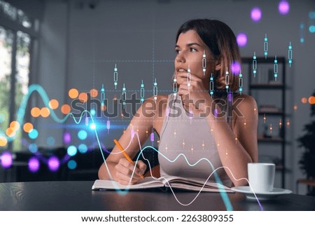 Smiling woman in casual wear taking notes in notebook at office workplace with coffee cup. Concept of distant business education, information technology, dreaming, thinking. Forex charts and graphs Royalty-Free Stock Photo #2263809355