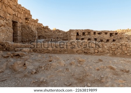 The remains of internal buildings in the rays of the rising sun in the ruins of the fortress of Masada - is a fortress built by Herod the Great on a cliff-top off the coast of the Dead Sea, Israel