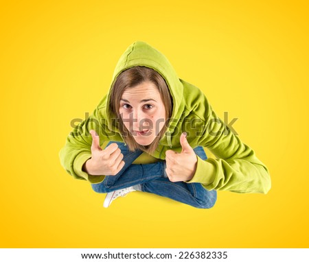 Young girl making Ok sign over yellow background 