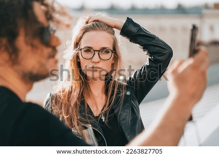 Serious young redhead woman with hipster boyfriend making selfie on rooftop. European couple reading news on phone. Financial troubles. Relationship difficulties. Woman in glasses frustrated. Model Royalty-Free Stock Photo #2263827705