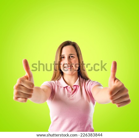 Young girl making Ok sign over green background 