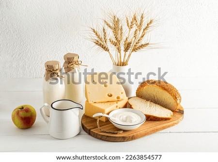 various dairy products, apples and a vase with a bouquet of ears on a white background. front view. the concept of the Jewish holiday of Shavuot. Royalty-Free Stock Photo #2263854577
