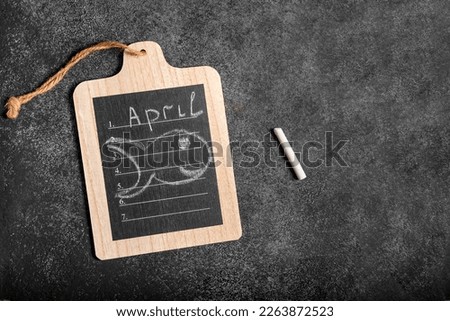Conceptual image of the calendar day April 1 with an empty space for text on a dark background in the form of a note on the board and an image of a fish