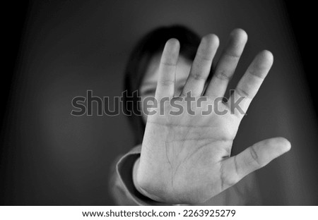 Defocused photo Girl showing stop sign gesture black and white photo. The child shows a palm, selectively focuses on five fingers. stop sign with hand saying no to domestic violence or abuse