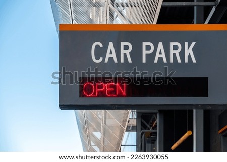 Car Park Open sign installed on building facade viewed from city street on a day