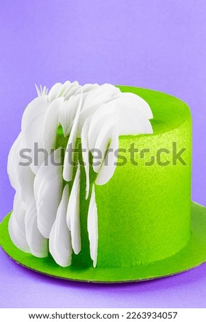 Cake with green cream icing and white leaf decorations on purple background, close up. Selective focus, copy space. Mardi Gras King Cake masquerade festival carnival