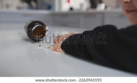 Caucasian Toddler Girl Picking Up and Swallowing Capsule Pill Medicine Left Unattended on Table by Unwary Parent Royalty-Free Stock Photo #2263943193