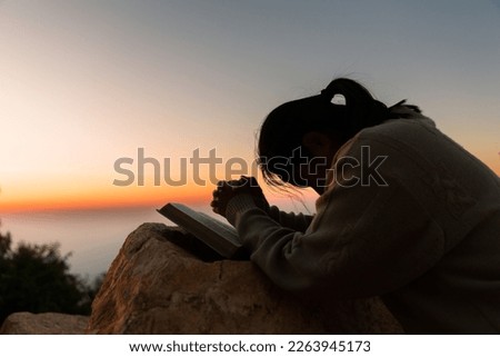 Silhouette of woman kneeling down praying for worship God at sky background. Christians pray to jesus christ for calmness. In morning people got to a quiet place and prayed. copy space. Royalty-Free Stock Photo #2263945173