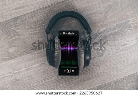 Smartphone playing music with headphones. Wooden background.
Radio broadcast audio streaming concept