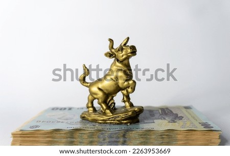 A miniature model of a bull with banknotes on white background Business concept, stock exchange, finance bull money