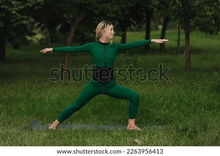A young beautiful girl is doing yoga in a calm warm evening on the grass.
