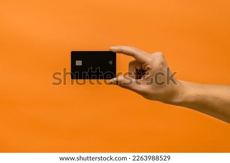 Man's hand holding credit card isolated on orange background Royalty-Free Stock Photo #2263988529