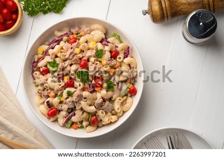 Homemade macaroni salad with elbow pasta and canned tuna, carrot, Purple cabbage, tomato, corn, green peas and mayonnaise dressing in a white plate on wooden table.Top view Royalty-Free Stock Photo #2263997201