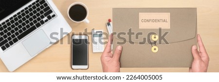 Man's hand holding confidential paper folder or important information for work or presentation to the organization. Royalty-Free Stock Photo #2264005005