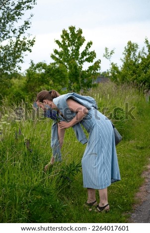 Woman picking flowers on the side of the road - Stock photo