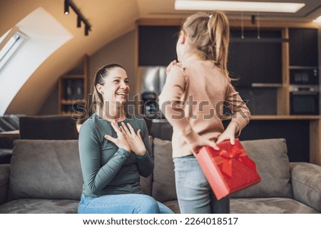 Happy mother is getting gift from her daughter.