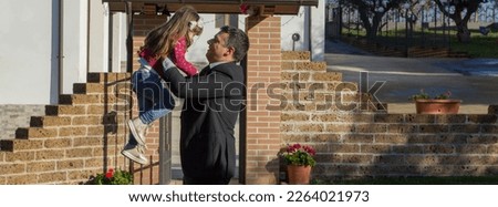 Image of a smiling dad who returns from work and is lovingly welcomed by his daughter who takes her in her arms. Horizontal banner 
