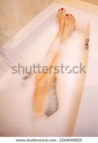 Woman legs in bath foam. Top view. Enjoying and relaxation in spa hotel