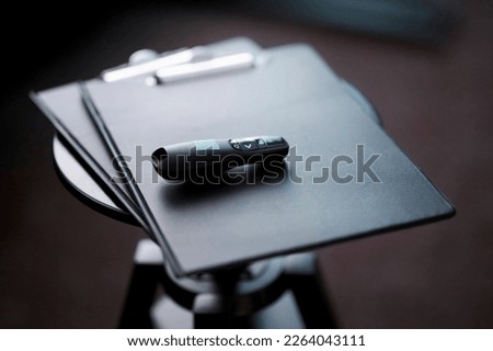 the clicker lies on the folder during the presentation. clicker for presentation lies on a black folder. Presentation laser pointer and clicker Royalty-Free Stock Photo #2264043111