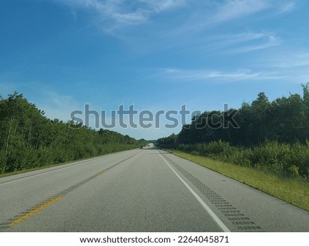 A wide open highway under a blue sky on a sunny summer day.