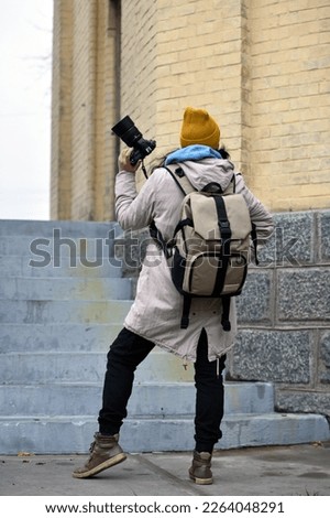 young girl photographer, with a camera. girl. woman tourist, photographer, blogger, journalist. woman photographer on a robot taking pictures, autumn or spring season, cold weather. back view