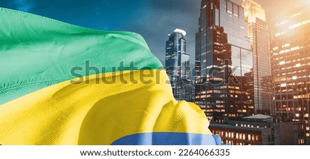 Gabon national flag cloth fabric waving on beautiful blue sky. Royalty-Free Stock Photo #2264066335