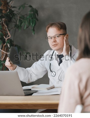 male doctor communicates with female patient in office, examines X-ray picture. in clinic male traumatologist is at reception, a virologist, immunologist, endocrinologist prescribes treatment drugs