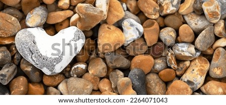 heart shaped white stone laying on pebble beach on the shore banner