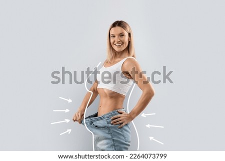 Happy positive middle aged pretty blonde lady wearing big jeans, showing loose in waist and smiling at camera, grey studio background, side view, copy space, collage Royalty-Free Stock Photo #2264073799