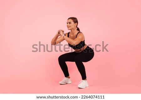 Beautiful Sporty Young Woman Doing Deep Squat Exercise Over Pink Background In Studio, Motivated Millennial Female Making Fitness Training Indoors, Enjoying Healthy Lifestyle, Copy Space
