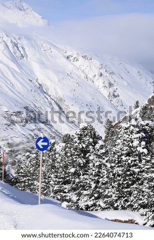 Blue piste sign backdropped by a beautiful snowy mountain and snowy trees in Obergurgl Ski Resort, Tyrol, Austria