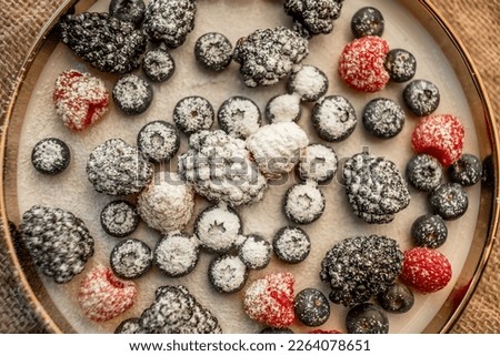 Raspberries and blackberries on a platter, sprinkled with powdered sugar. Healthy food on a plate