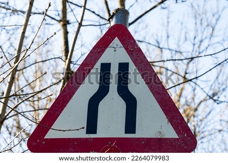 UK Traffic sign stating road narrows ahead with a red and white warning triangle