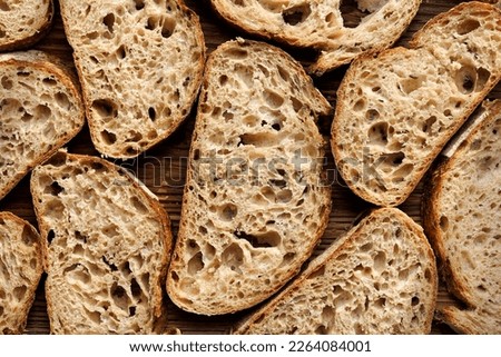 Sourdough bread slices on wooden background, top view. Bread background Royalty-Free Stock Photo #2264084001