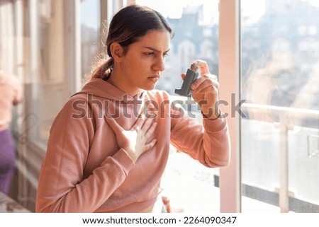An asthmatic girl who takes an inhaler and has an asthma attack. She has a problem with asthma and holding an inhaler. Royalty-Free Stock Photo #2264090347
