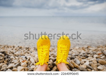 relaxed person with feet in yeallow sneakers on the beach