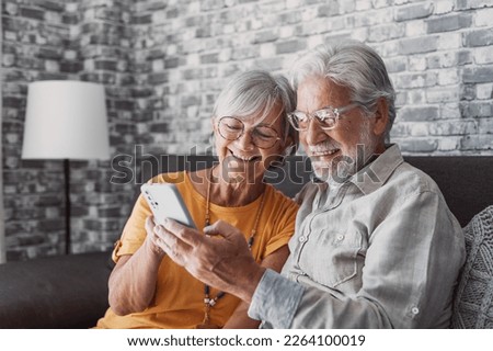 Elderly grandfather and grandmother spend time having fun using smartphone apps, middle-aged wife enjoy online entertainments, taking selfie with old husband, older generation and modern tech concept Royalty-Free Stock Photo #2264100019