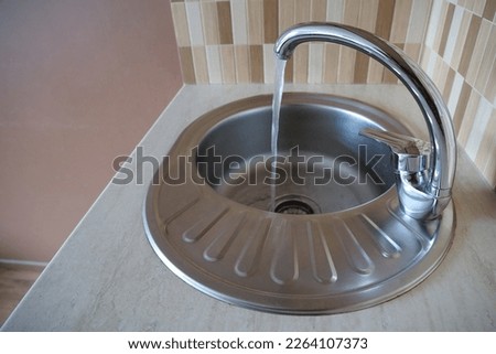 From the tap is flows water. Water pours in a strong stream from the tap in kitchen